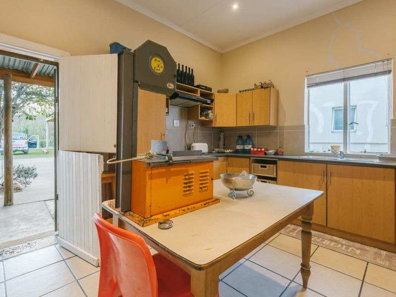A functional kitchen featuring laminate cabinetry, tiled flooring, and direct access to the exterior, requiring cosmetic updates to improve its overall condition.