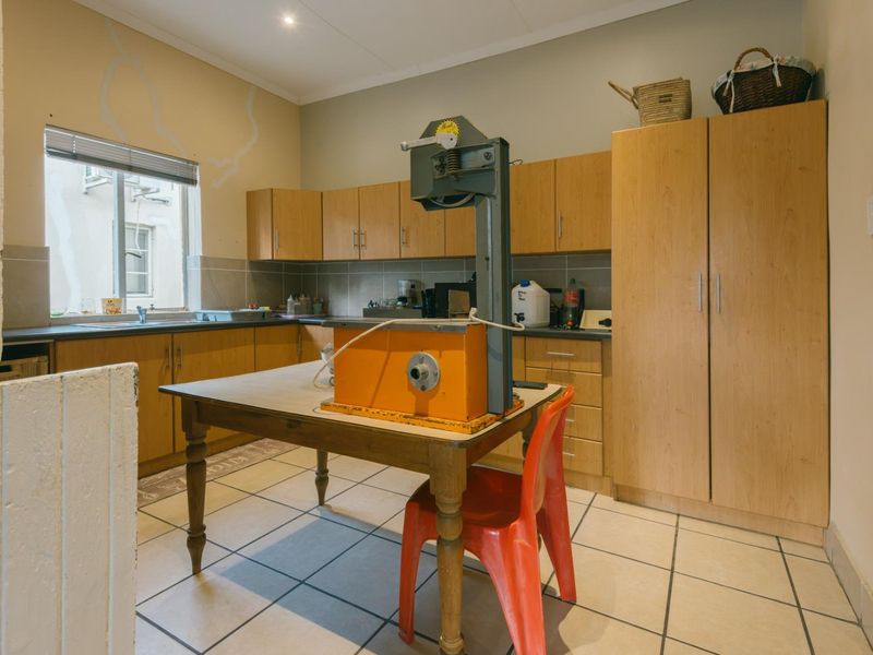 A functional kitchen featuring light wood cabinetry, tiled flooring, and a tiled backsplash, offering a practical layout with ample storage space.