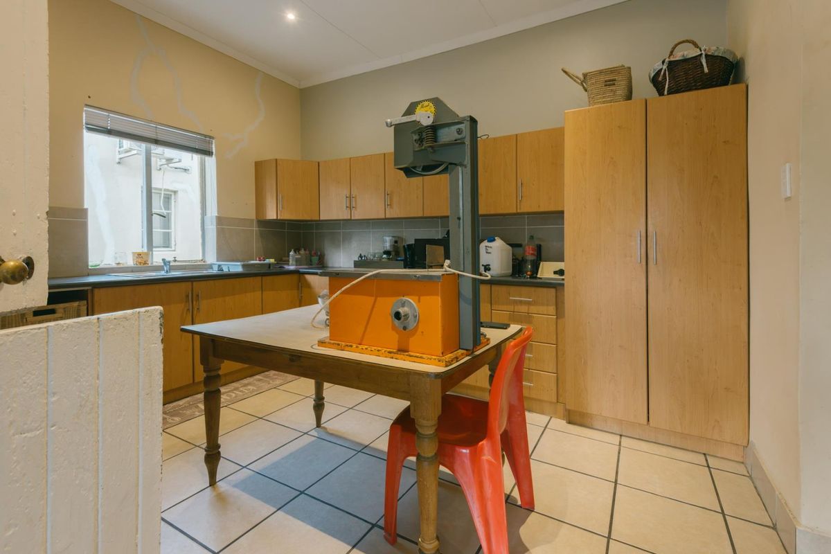 A functional kitchen featuring light wood cabinetry, tiled flooring, and a tiled backsplash, offering a practical layout with ample storage space.