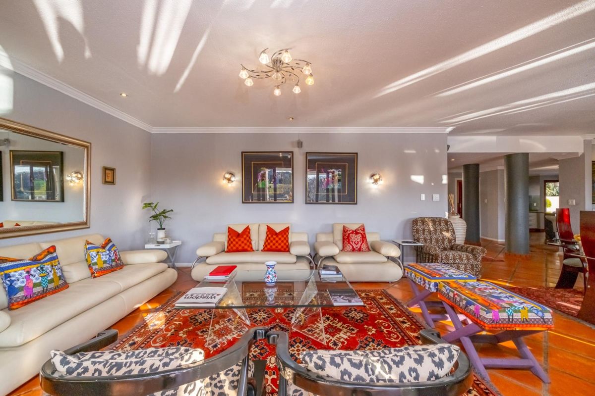 Spacious living room featuring terracotta floor tiles, recessed downlighting, and decorative wall sconces, creating a warm and inviting atmosphere.
