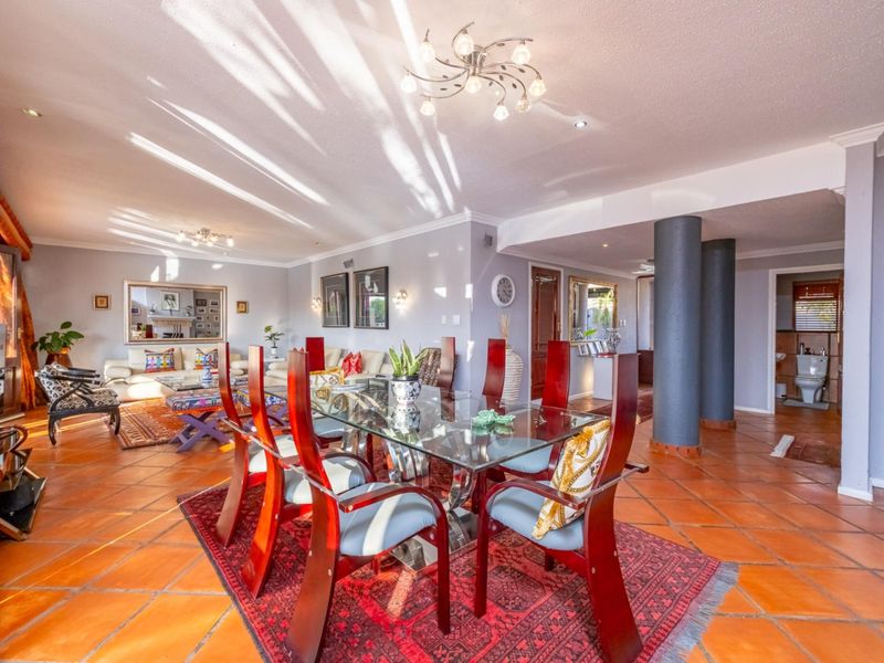 Spacious open-plan living and dining area featuring terracotta floor tiles, structural columns, and neutral wall finishes with ample natural light.