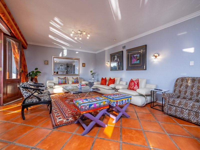 Spacious living room featuring traditional terracotta floor tiles, crown molding, and direct access to an outdoor patio area through sliding glass doors.