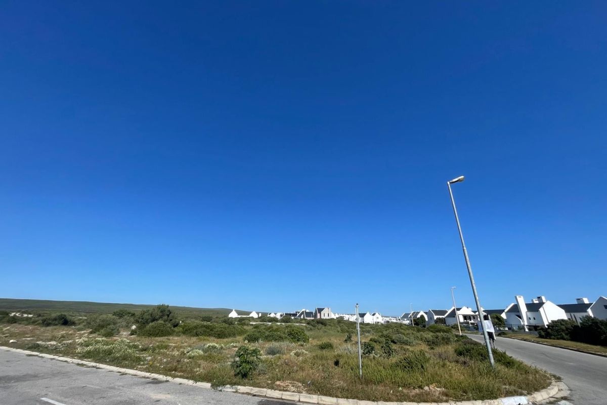 A view of a vacant residential plot situated on a corner lot with established street infrastructure and surrounding residential development.