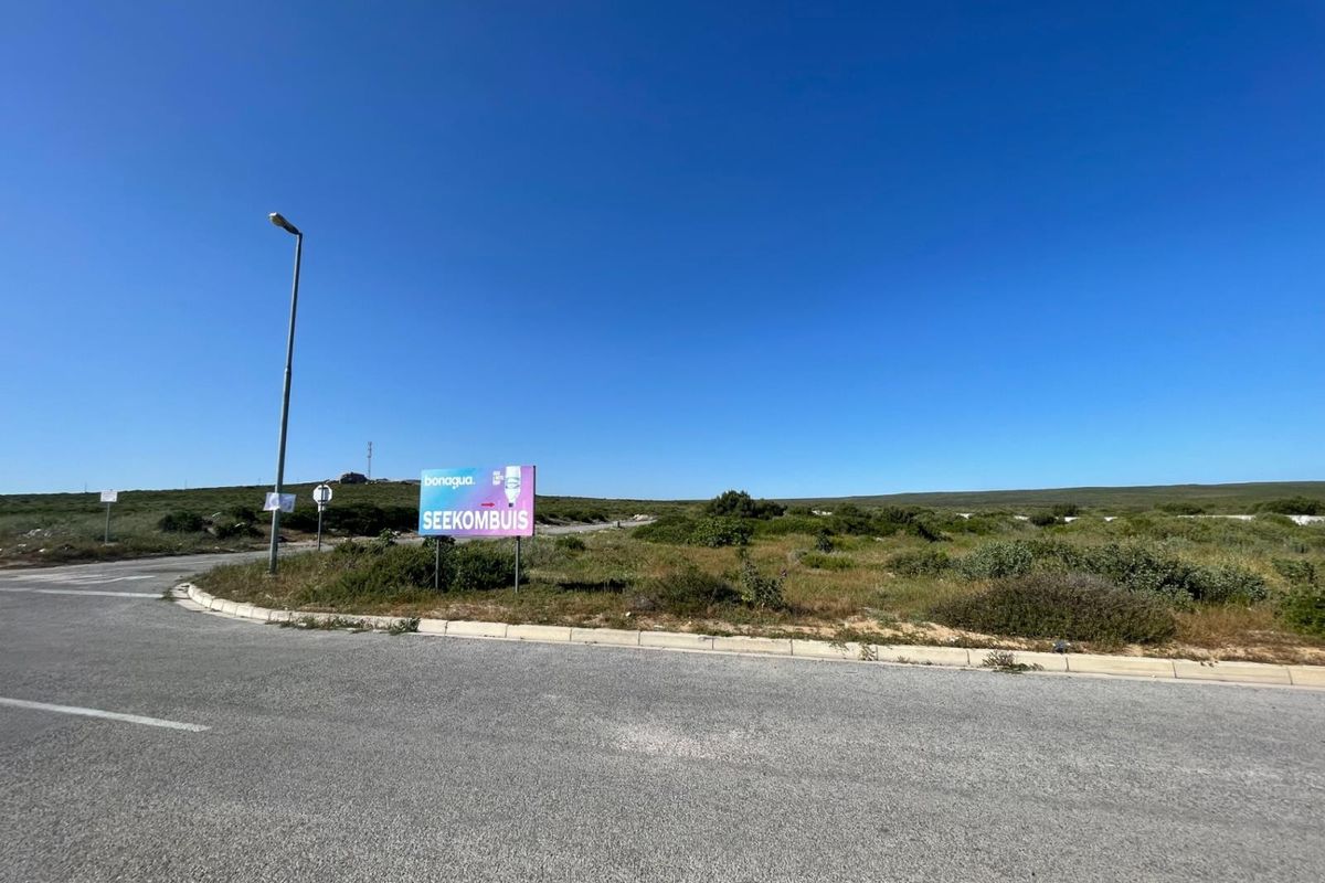 A view of the street frontage and surrounding vacant land area with a prominent signage board.