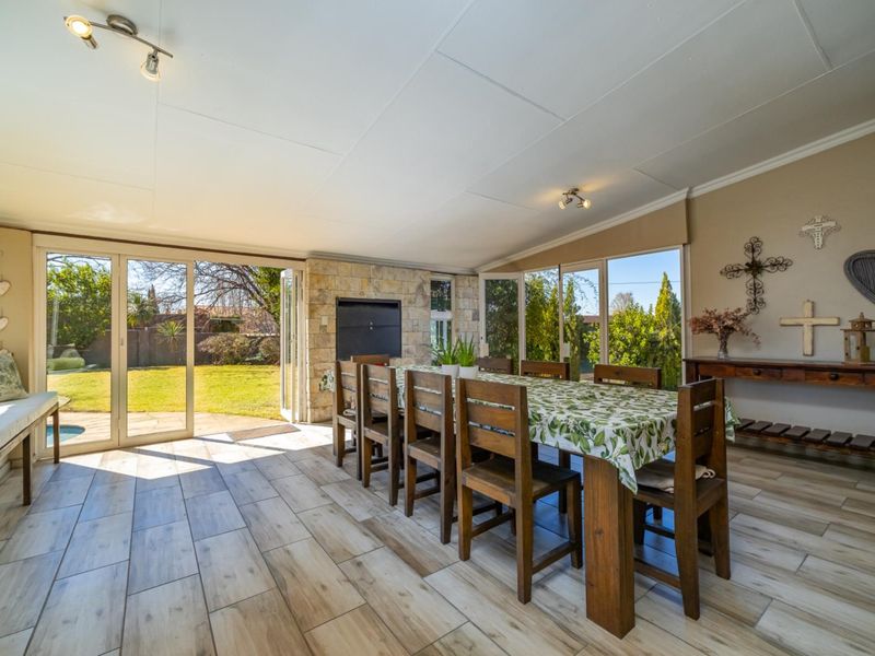 Spacious dining room featuring wood-look tiled floors, a stone-clad built-in fireplace, and large sliding glass doors providing seamless access to the garden.