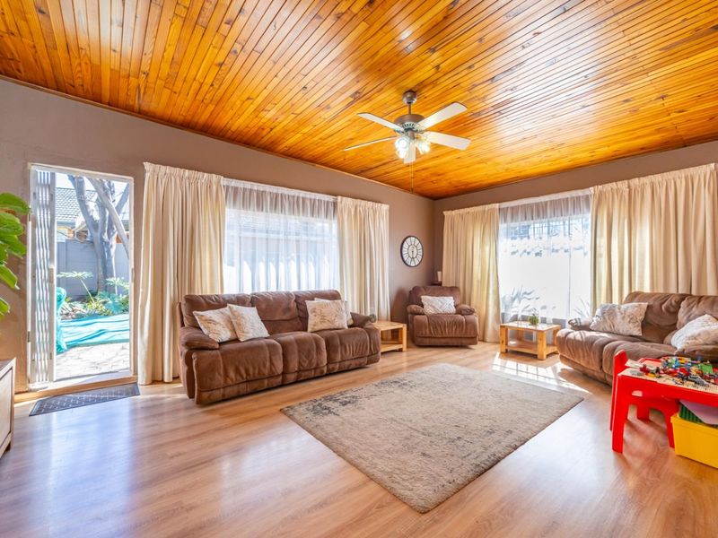 Spacious living room featuring a warm timber tongue and groove ceiling, laminate flooring, and direct access to the outdoor patio area.