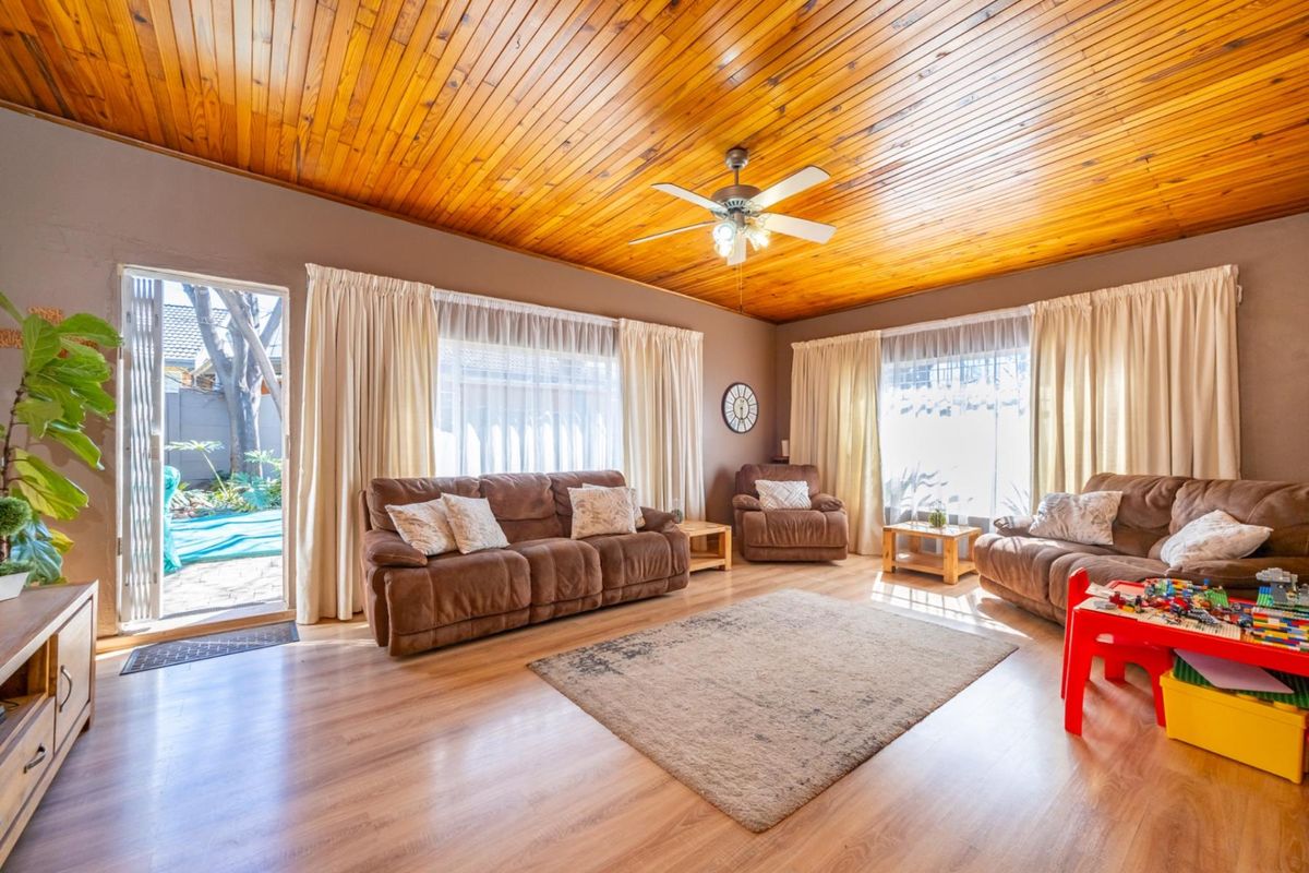 Spacious living room featuring a warm timber tongue and groove ceiling, laminate flooring, and direct access to the outdoor patio area.
