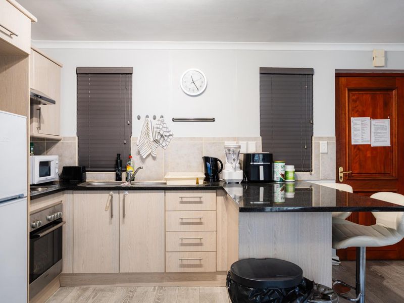 A functional kitchen featuring light wood cabinetry, granite countertops, a built-in oven, and a breakfast bar area with a tiled backsplash.