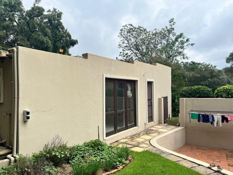 Rear exterior view of the cottage featuring a paved walkway, brick patio area, and access via timber-framed sliding doors.
