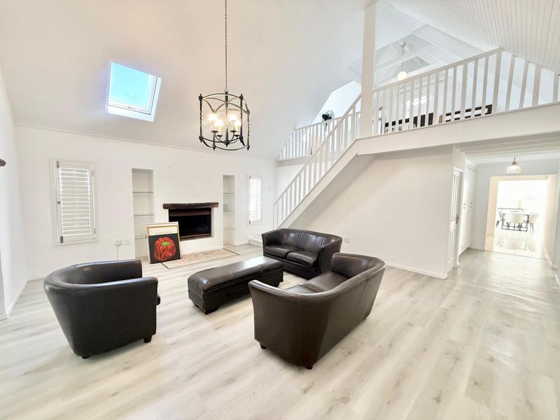 Spacious living room featuring a fireplace, vaulted ceilings with a skylight, and a mezzanine level overlooking the main area.