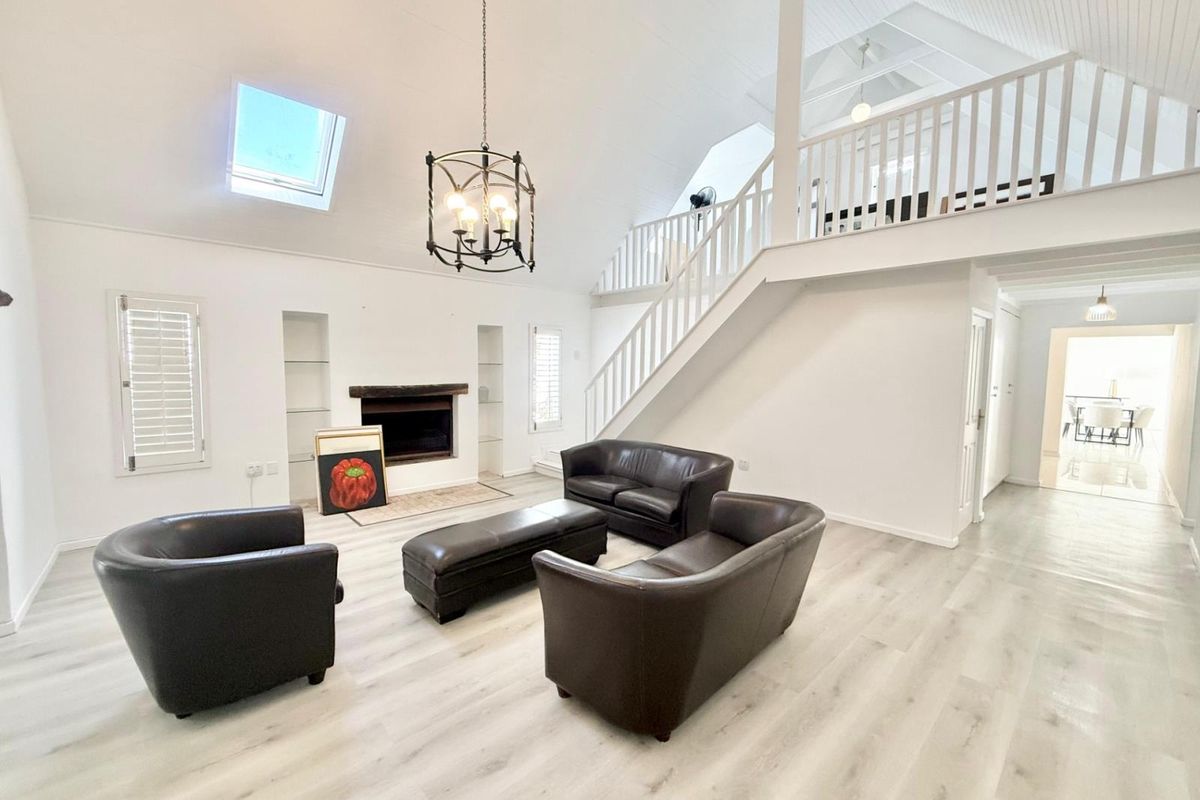 Spacious living room featuring a fireplace, vaulted ceilings with a skylight, and a mezzanine level overlooking the main area.