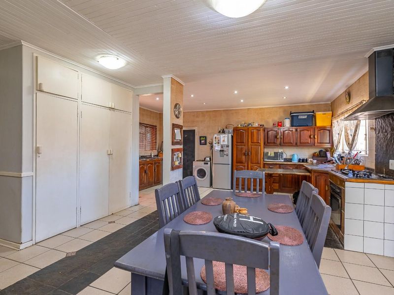 Open-plan kitchen and dining area featuring wooden cabinetry, tiled flooring, built-in oven, and extractor fan, offering a functional layout with potential for modernization.