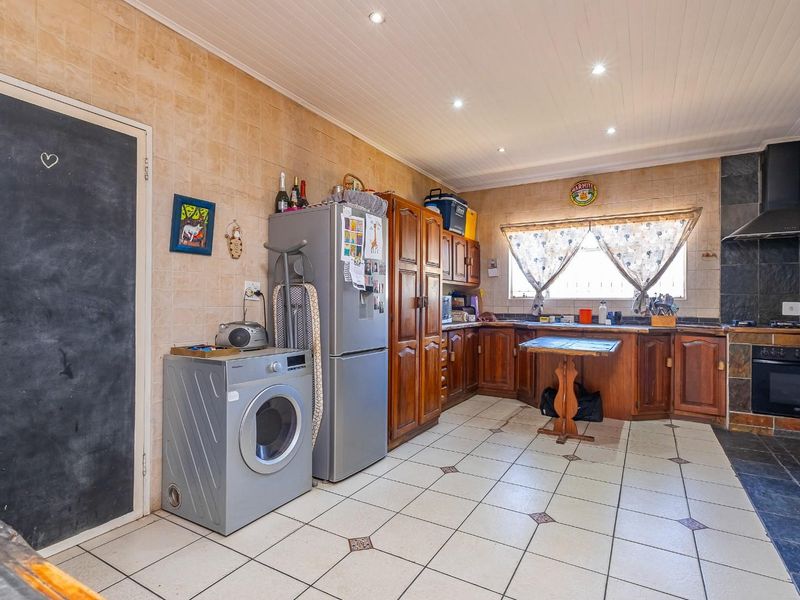 A functional kitchen featuring wooden cabinetry, tiled splashbacks, built-in oven with extractor fan, and recessed ceiling lighting.