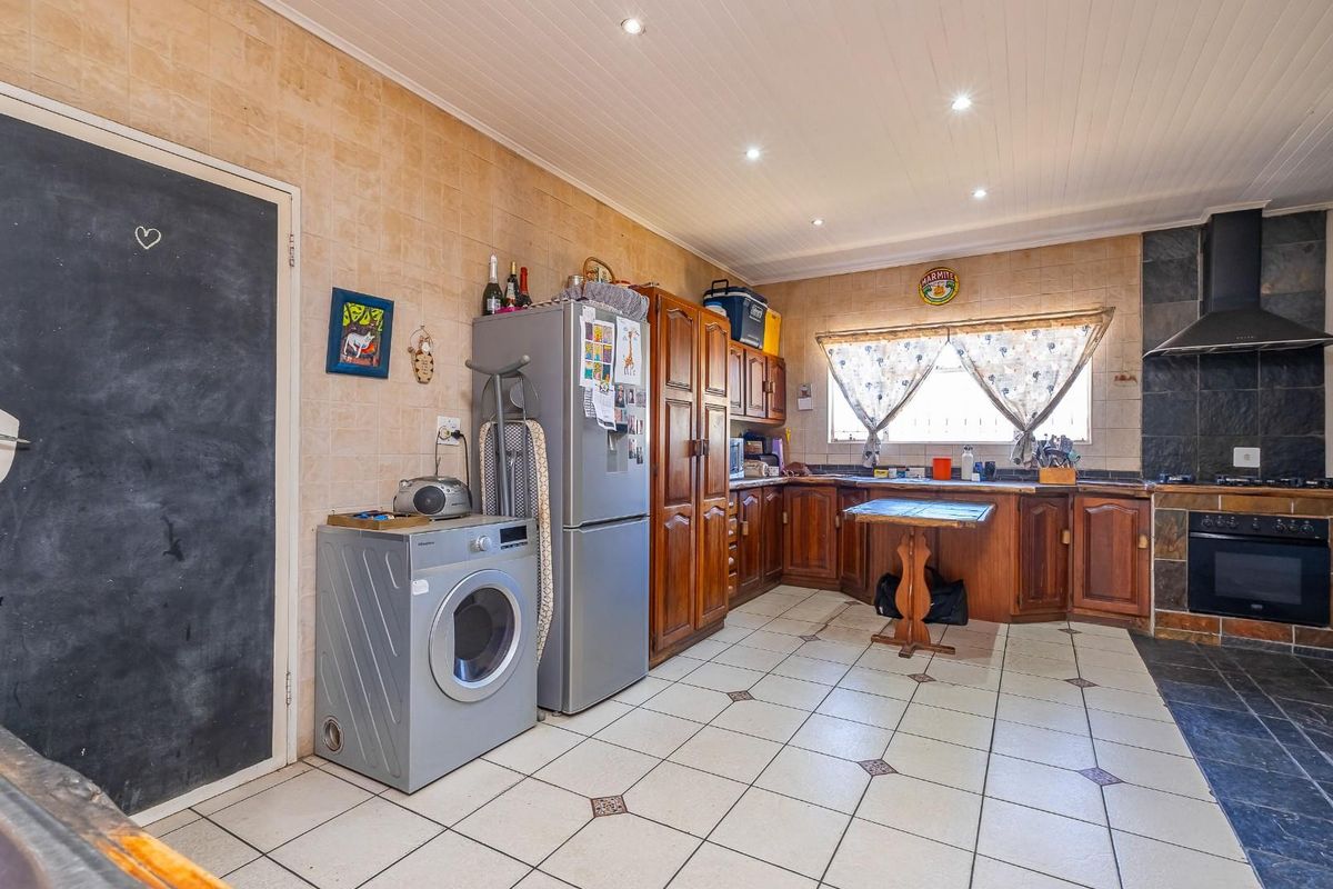A functional kitchen featuring wooden cabinetry, tiled splashbacks, built-in oven with extractor fan, and recessed ceiling lighting.