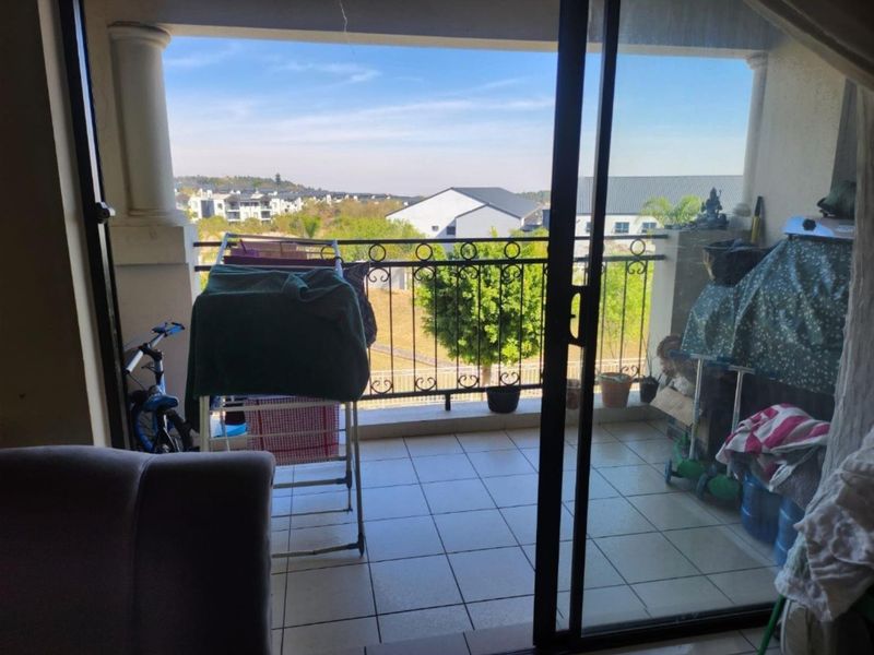 A covered balcony featuring tiled flooring, a wrought iron balustrade, and sliding glass door access, offering an elevated view of the surrounding residential area.