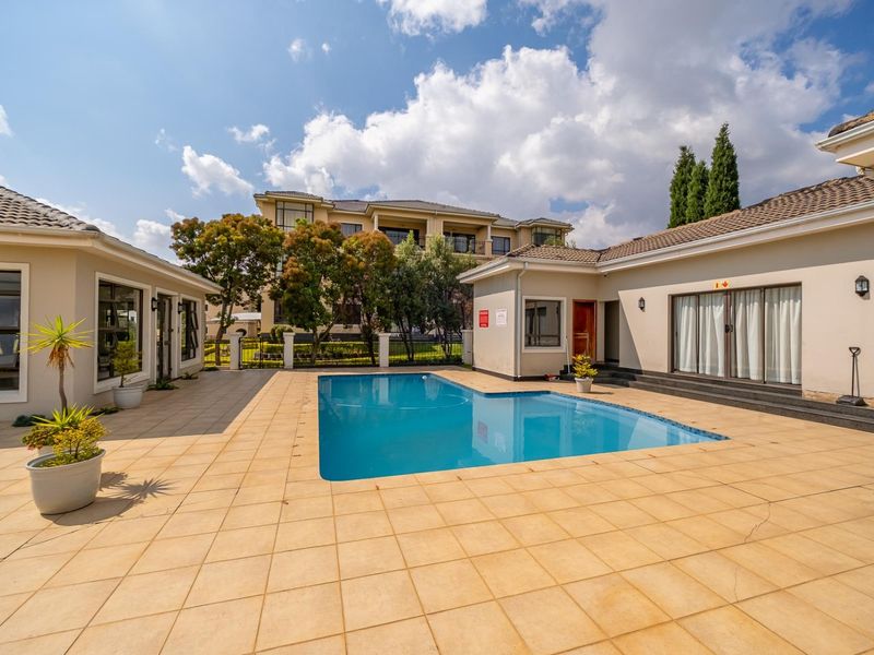 Outdoor pool area featuring a swimming pool with a tiled deck, surrounded by residential building wings with sliding glass door access.