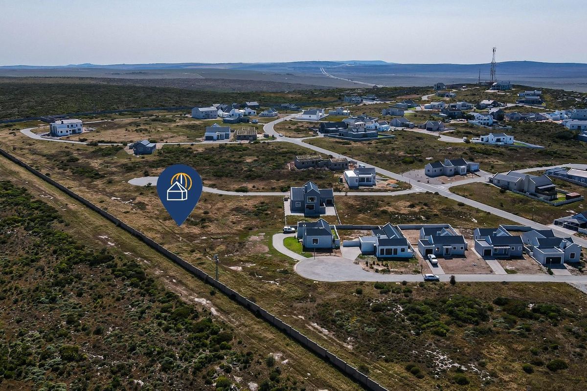 Aerial view of a residential estate featuring vacant land plots, established homes, and surrounding natural landscape.