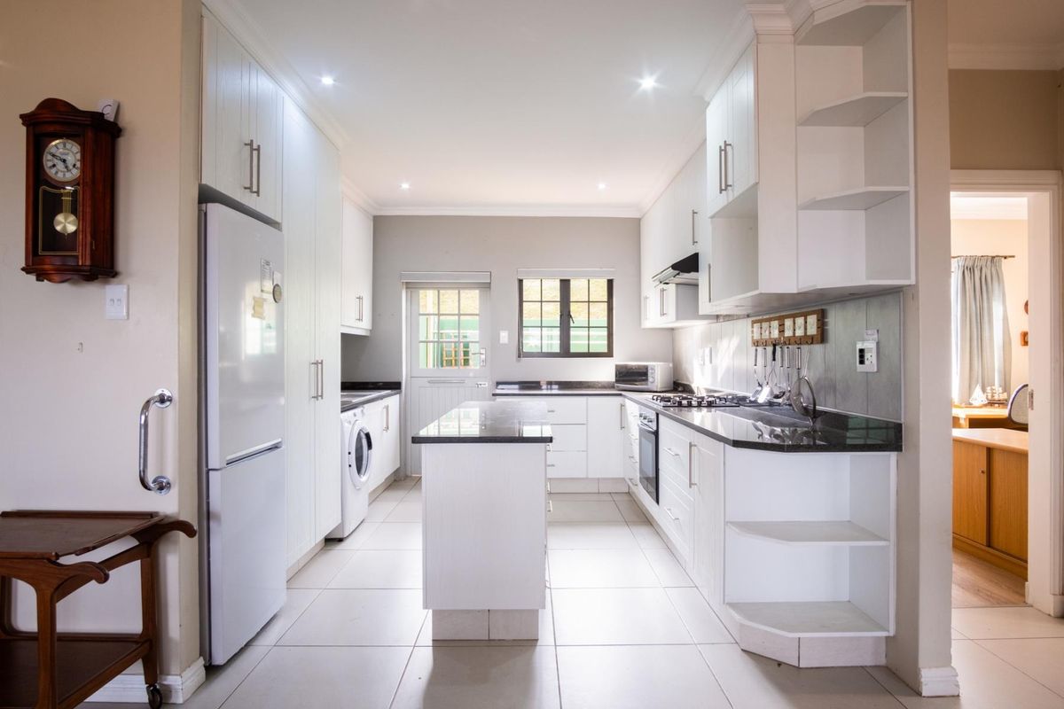 Modern kitchen featuring white cabinetry, granite countertops, a central island, built-in oven, gas hob, and tiled flooring with recessed lighting.