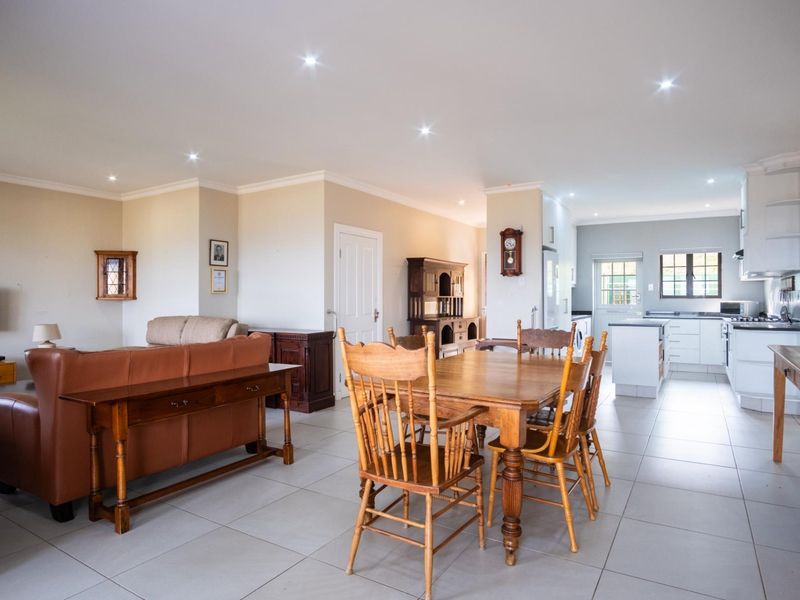 Spacious open-plan living, dining, and kitchen area featuring modern tiled flooring, recessed lighting, and a functional kitchen with built-in cabinetry and appliances.