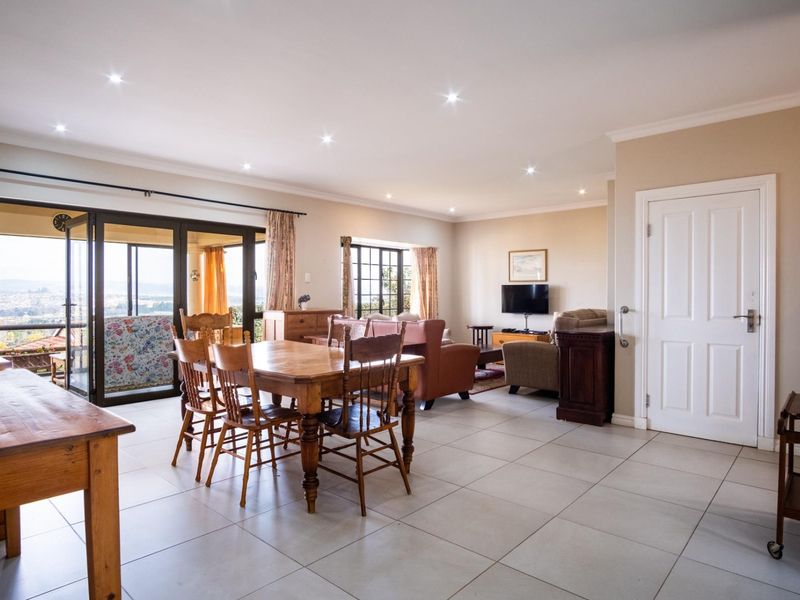 Spacious open-plan living and dining area featuring neutral tiled flooring, recessed lighting, and large sliding doors providing access to an outdoor balcony.