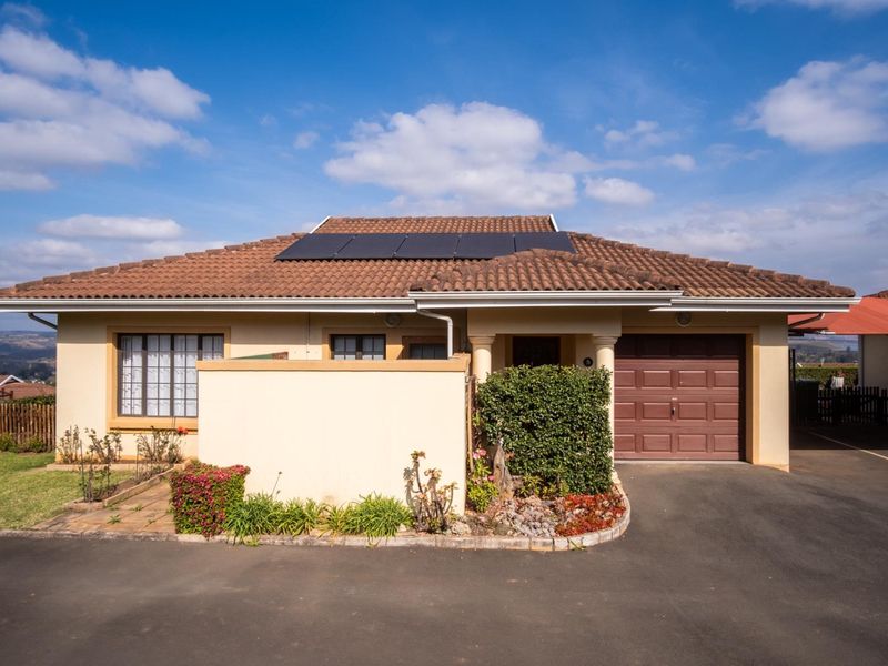 Front elevation of a townhouse featuring a tiled roof with solar panels, a single garage, and a paved driveway.