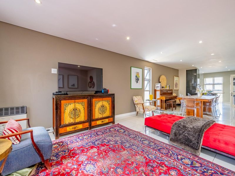 Spacious open-plan living and dining area featuring neutral wall tones, polished tiled flooring, and recessed lighting, flowing seamlessly into the kitchen space.
