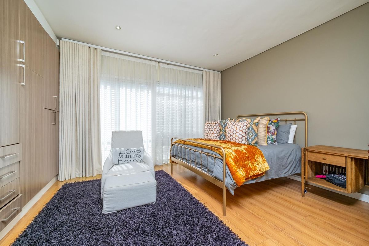 A well-maintained bedroom featuring laminate flooring, built-in cupboards, and floor-to-ceiling curtains, providing a bright and comfortable living space.