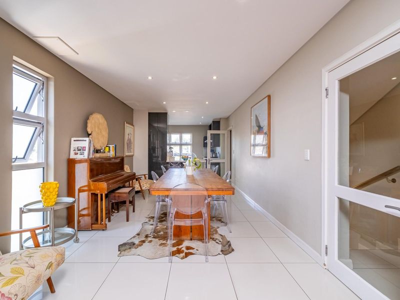 Spacious open-plan dining area featuring modern tiled flooring, recessed downlighting, and large windows providing ample natural light.