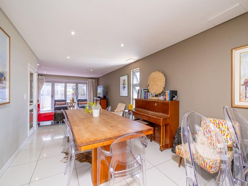 Spacious open-plan living and dining area featuring polished tiled flooring, recessed lighting, and large sliding glass doors leading to an outdoor space.