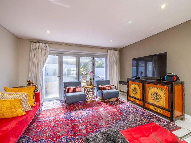 A bright living room featuring tiled flooring, recessed downlights, and large aluminium-framed sliding doors providing direct access to the outdoor area.