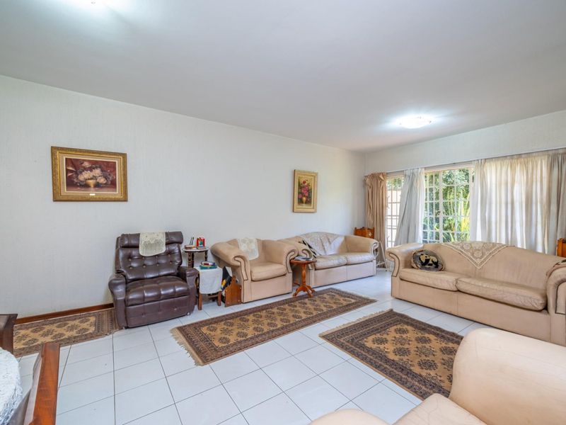 A spacious living room featuring white tiled flooring and large windows that provide ample natural light.