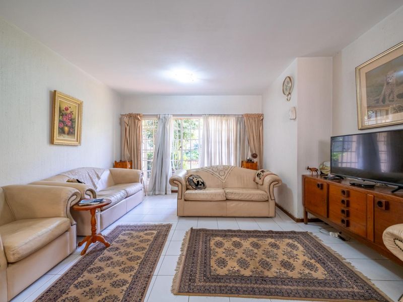 A spacious living room featuring neutral tiled flooring and a sliding glass door providing access to the outdoor area.