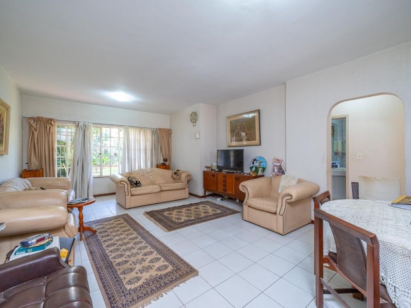 Spacious living room featuring tiled flooring, large windows allowing natural light, and an arched entryway leading to adjacent areas.