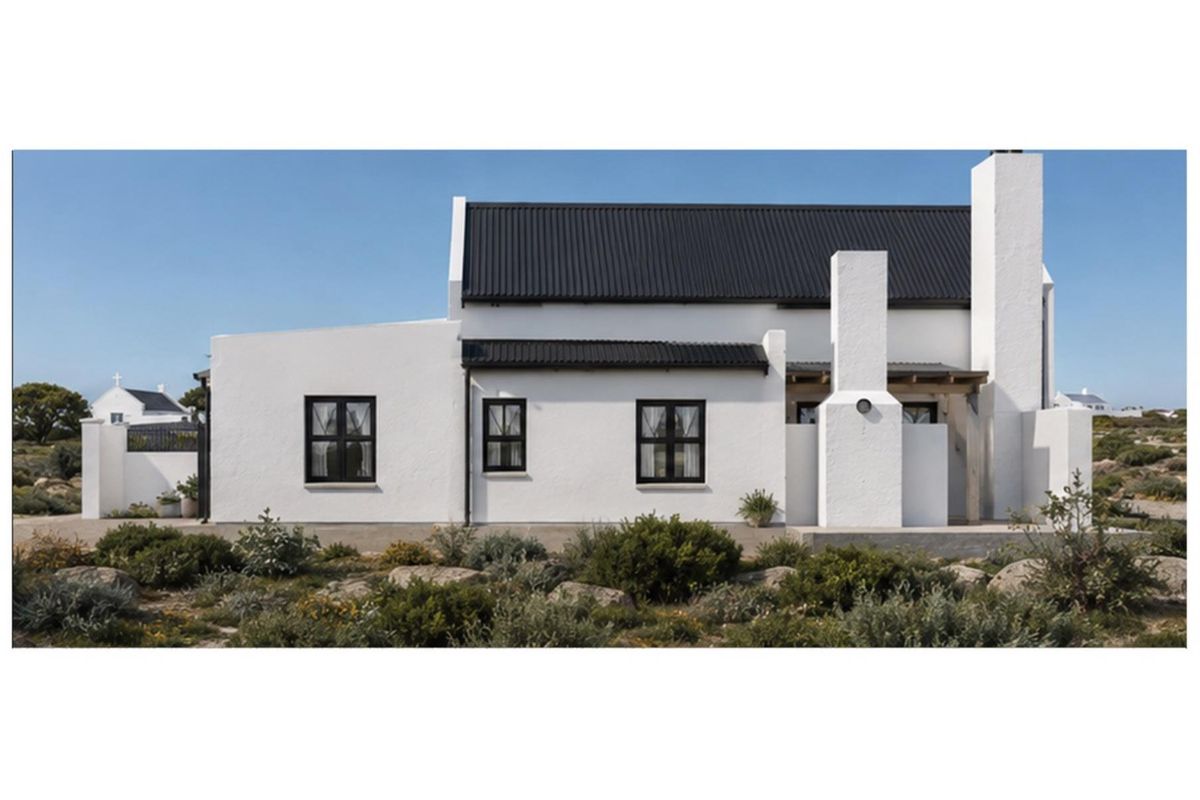 A well-maintained white cottage with a black corrugated metal roof, black-framed windows, and a prominent masonry chimney set against a natural landscape.