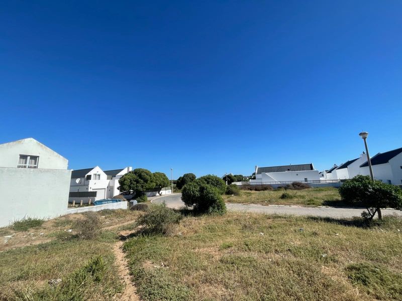 A street view showing the surrounding residential neighborhood with paved roads and established housing in a coastal estate setting.