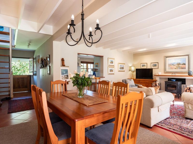 Spacious open-plan living and dining area featuring exposed beam ceilings, a cozy wood-burning stove, and a timber staircase leading to the upper level.