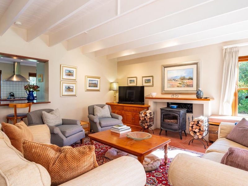 Spacious open-plan living area featuring a cozy wood-burning stove, exposed beam ceilings, and a convenient pass-through window connecting to the kitchen.