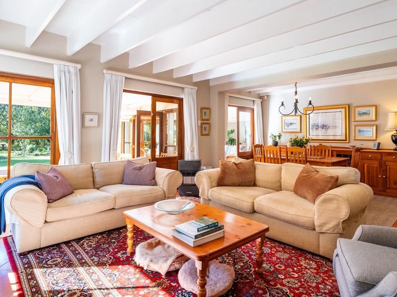 Spacious open-plan living and dining area featuring exposed timber ceiling beams, terracotta flooring, and large timber-framed doors providing access to the garden.