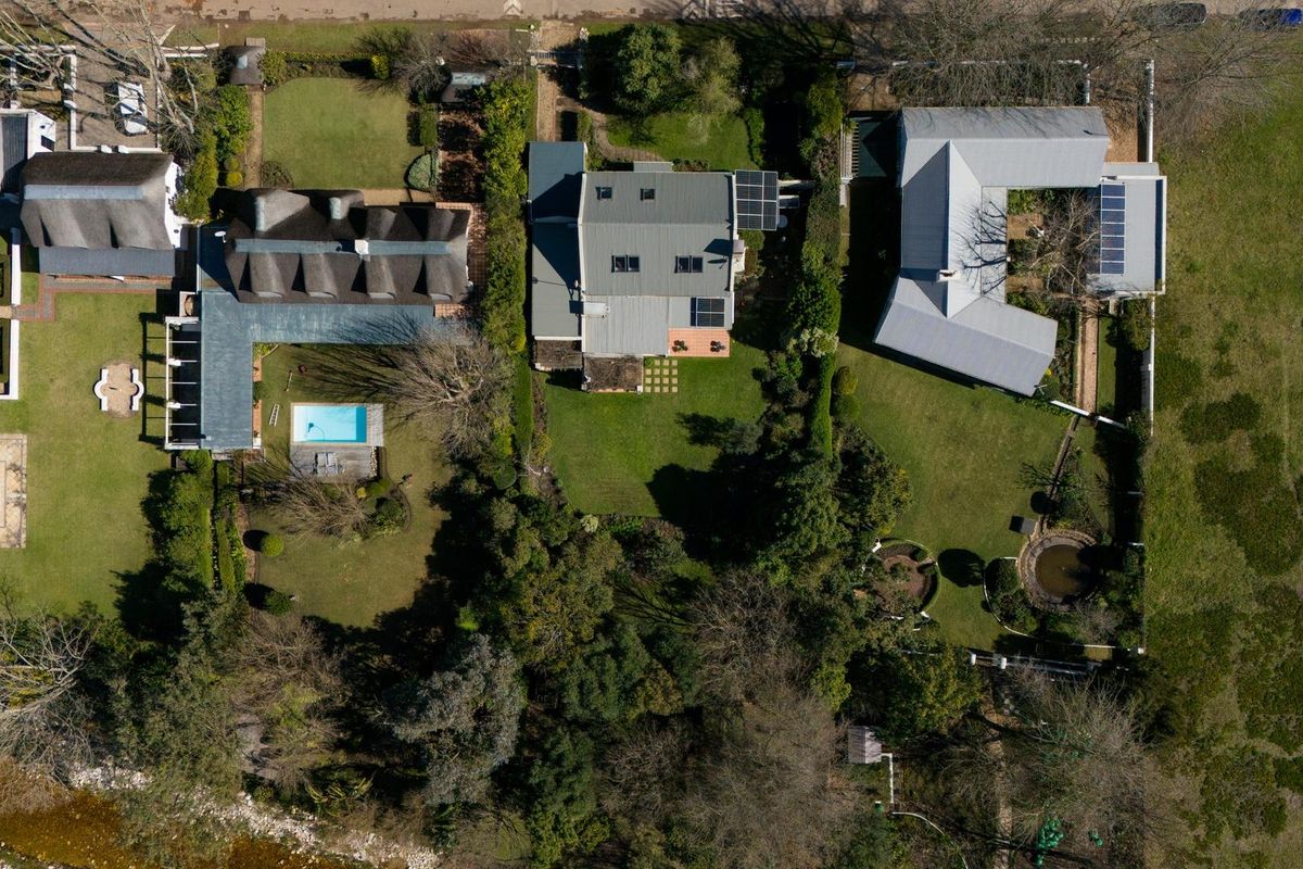 Aerial view of a residential property complex featuring multiple dwellings, swimming pools, solar installations, and established garden areas.