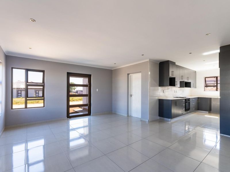 Spacious open-plan living area featuring modern tiled floors, recessed lighting, and a contemporary kitchen with built-in cabinetry and appliances.