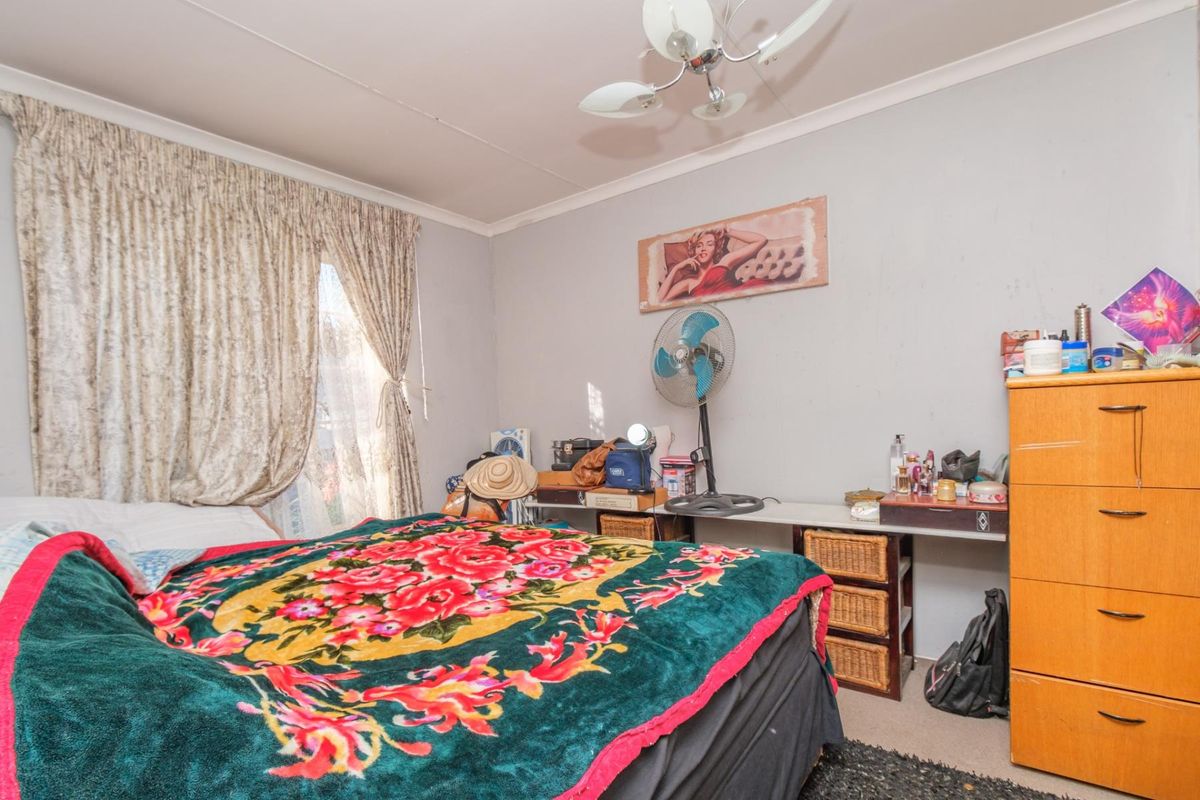 A bedroom featuring a ceiling fan and window curtains, requiring cosmetic updates to the wall finishes to improve the overall aesthetic.