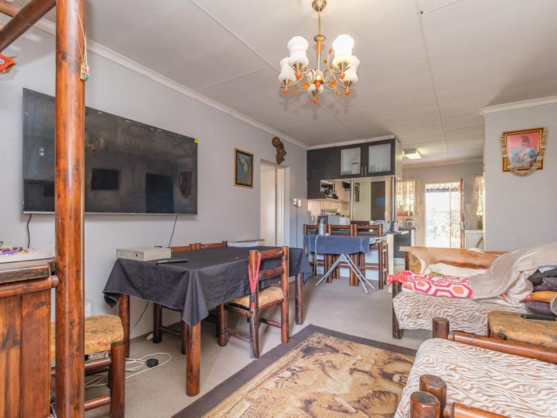 Open plan living and dining area featuring carpeted flooring and an adjoining kitchen with built-in cabinetry and functional workspace.