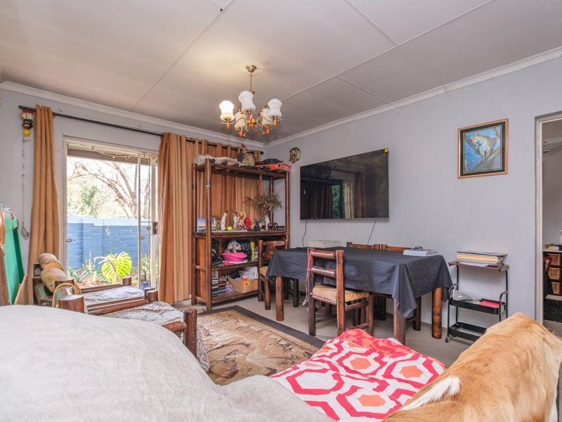 A living room featuring a sliding glass door leading to the exterior, with a tiled ceiling and wall-mounted television.