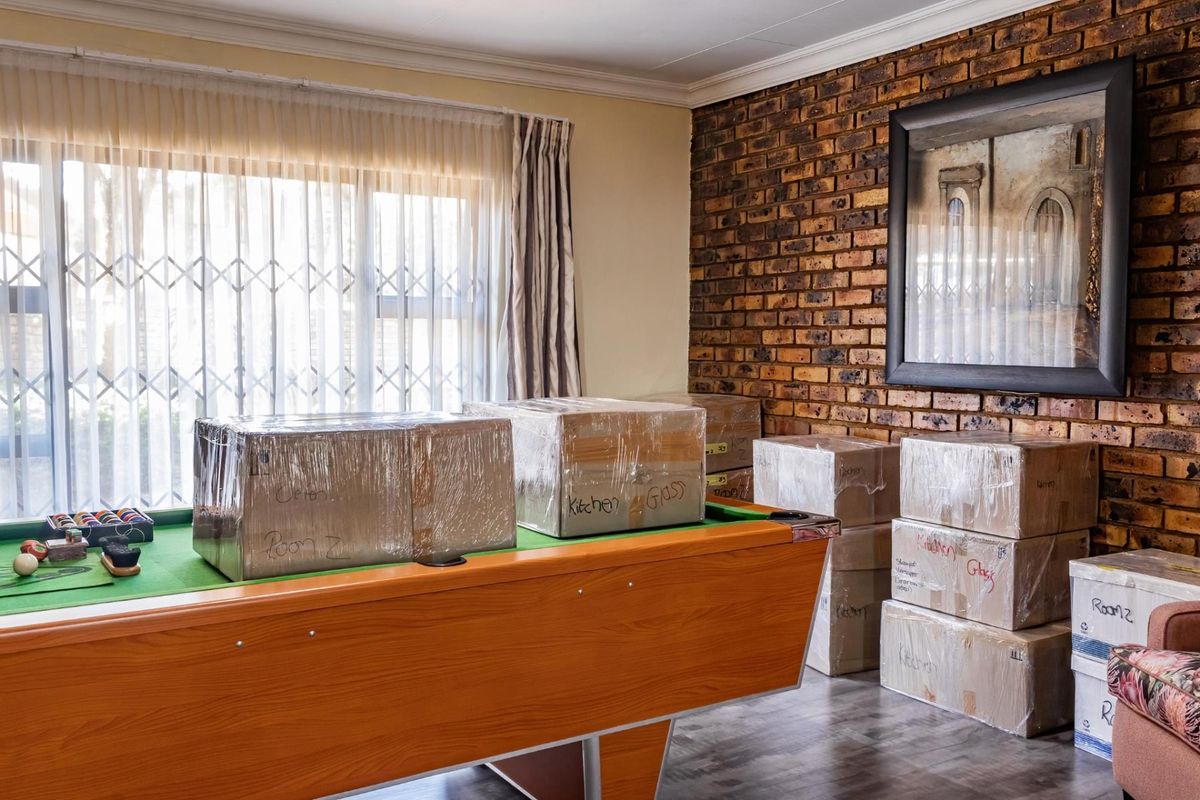 Living area featuring an exposed brick feature wall, laminate flooring, and a security gate over the window.