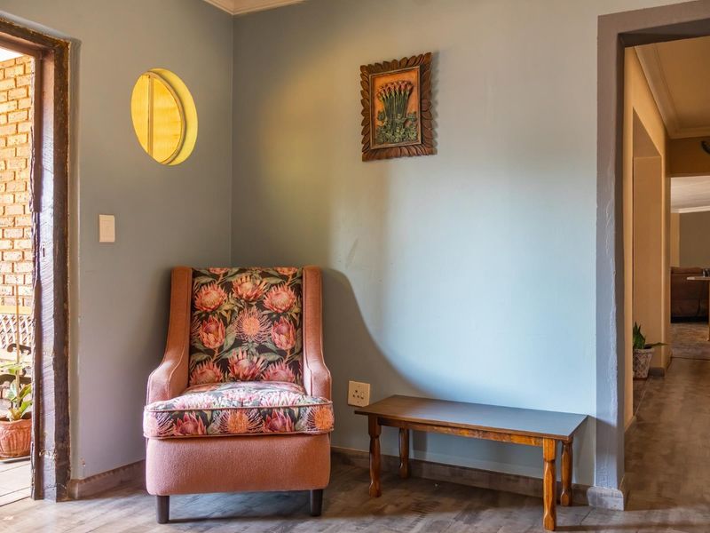 A hallway area featuring laminate flooring, a unique circular window, and access to adjacent rooms.