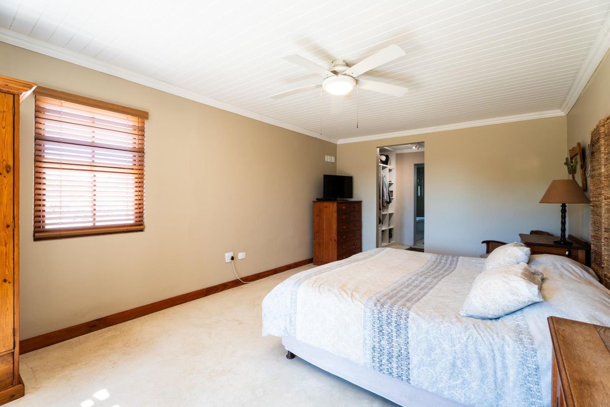Spacious bedroom featuring a tongue and groove ceiling, ceiling fan, and an integrated walk-in closet with neutral wall finishes.