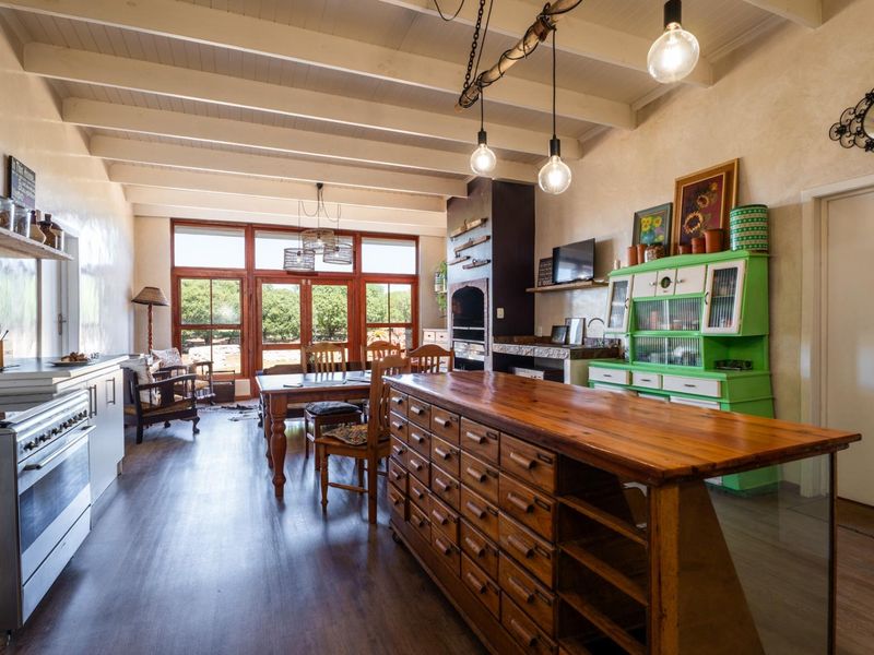 Spacious open-plan living and kitchen area featuring exposed beam ceilings, a built-in fireplace, and large windows overlooking the garden.