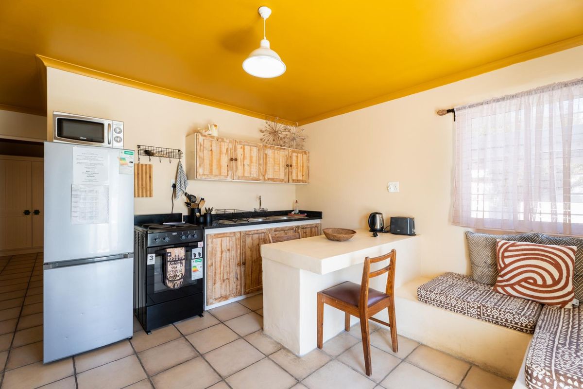 Compact kitchen featuring built-in cabinetry, a breakfast bar, integrated bench seating, and tiled flooring, offering a functional layout with potential for modern updates.