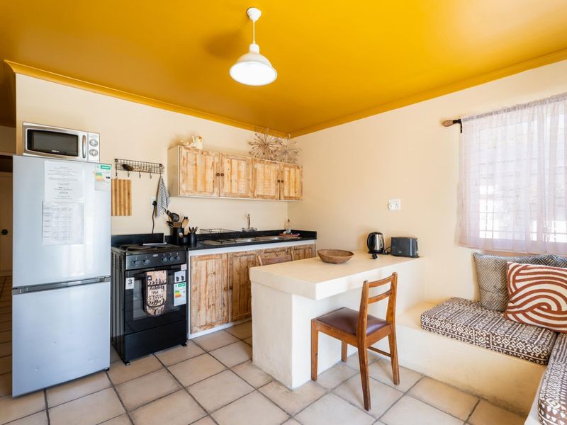 Compact kitchen featuring built-in cabinetry, a breakfast bar, integrated bench seating, and tiled flooring, offering a functional layout with potential for modern updates.