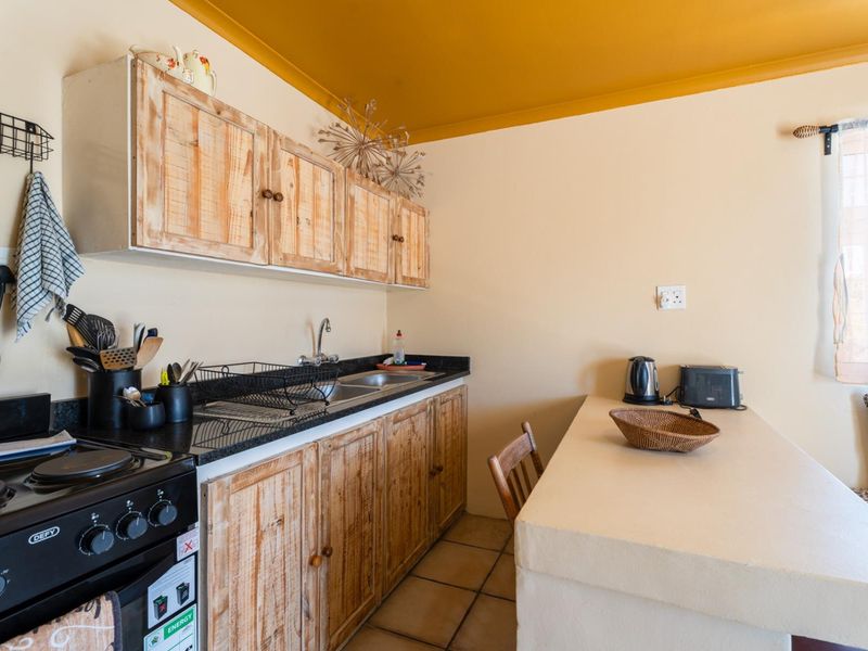 A functional kitchen featuring wooden cabinetry, granite countertops, a built-in stove, and a convenient breakfast counter with tiled flooring.